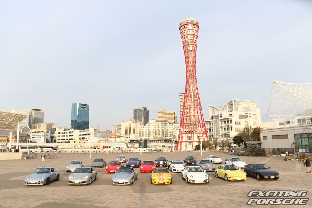 2025 年 EXCITING PORSCHE(神戸)で、神戸ポートタワーを背に並んだ参加者のポルシェ